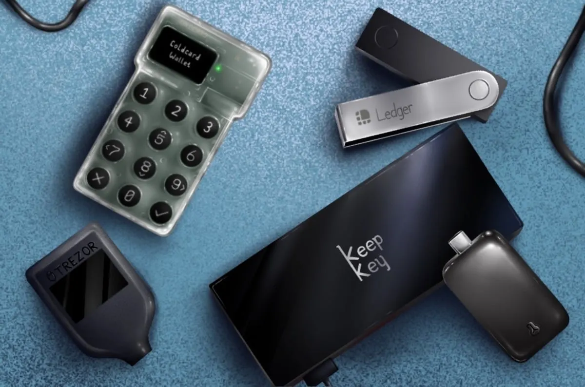 Several hardware wallets on a blue surface, including Coldcard, Ledger, Trezor and KeepKey devices